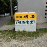 明石食堂の看板。民宿と食堂が併設されていることを示す、黄色と白のツートーン看板